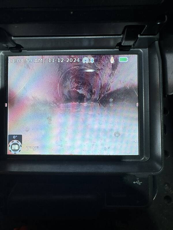Sewer inspection camera monitor showing the inside of a pipe, with a time and date stamp and a distance readout